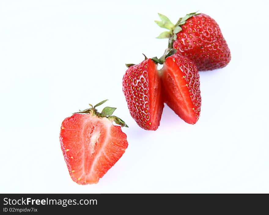 Strawberries on white background (a whole one, a half and one cut in half)