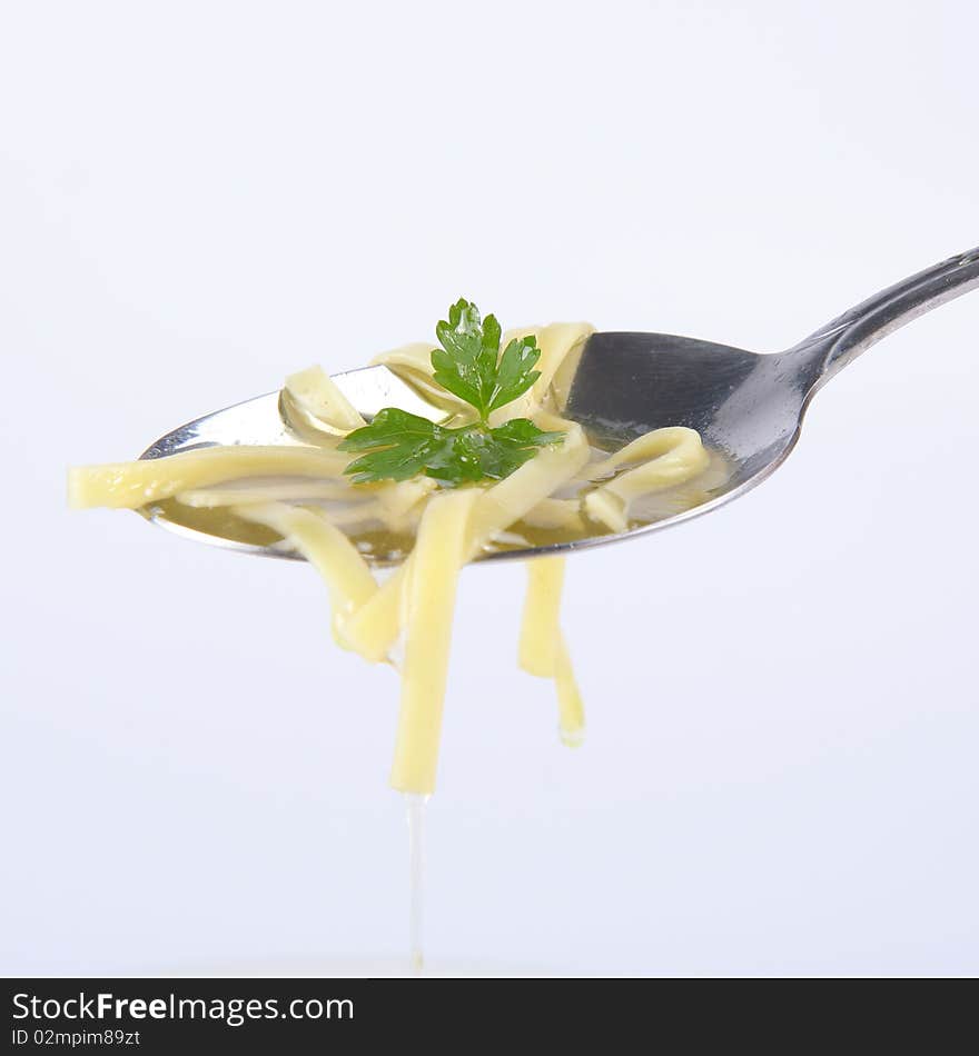 Chicken soup with macaroni decorated with parsley on a spoon. Chicken soup with macaroni decorated with parsley on a spoon