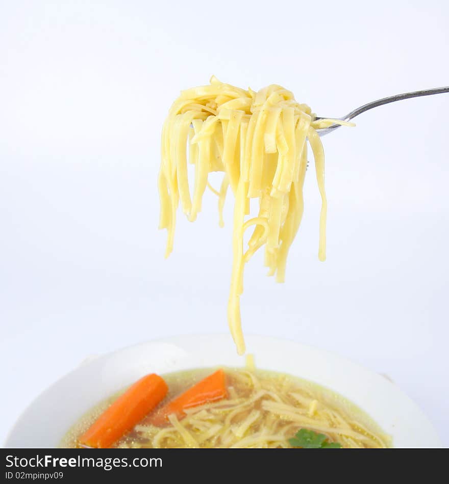 Chicken soup with macaroni and carrots decorated with parsley on a plate, some of it on a spoon. Chicken soup with macaroni and carrots decorated with parsley on a plate, some of it on a spoon