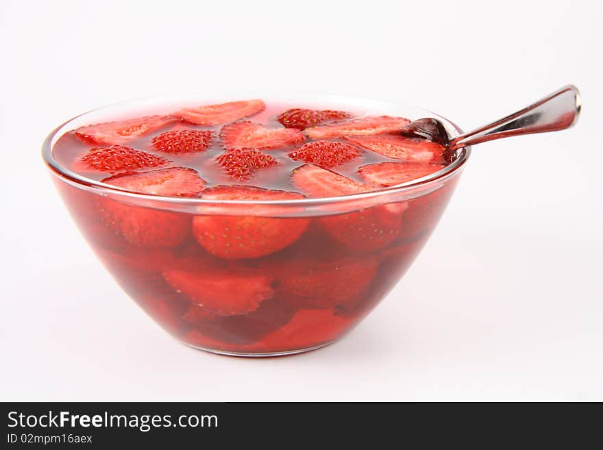 Jelly with strawberries in a bowl and a spoon