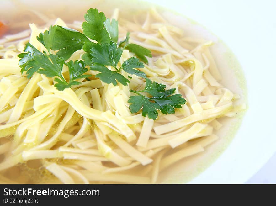 Chicken soup with macaroni decorated with parsley on a plate in close up