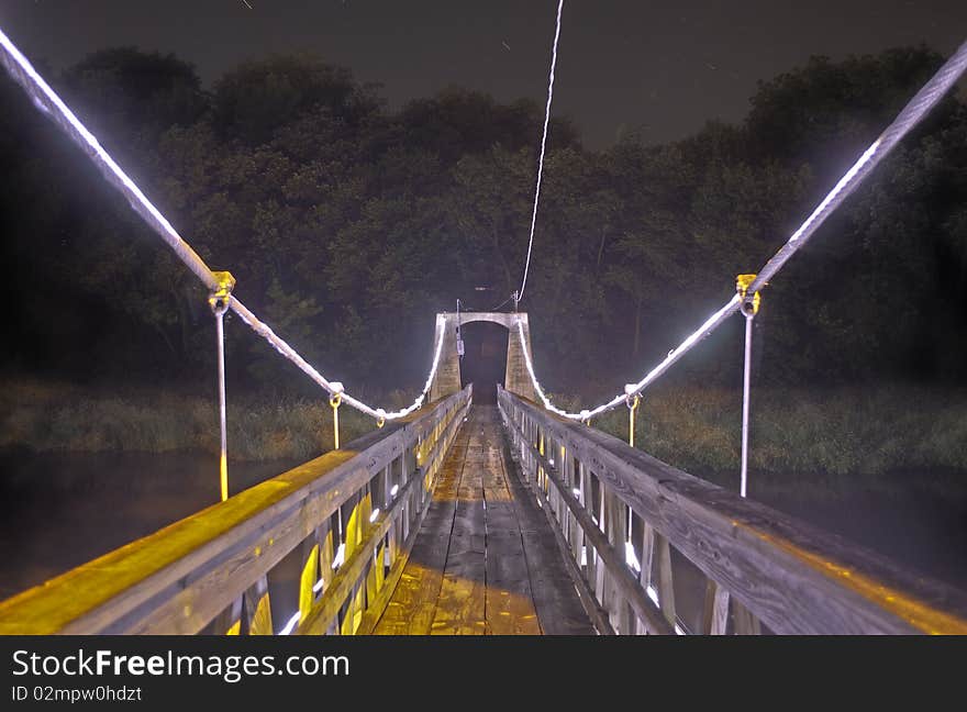 A Bridge with lights leading to a dark forest. A Bridge with lights leading to a dark forest