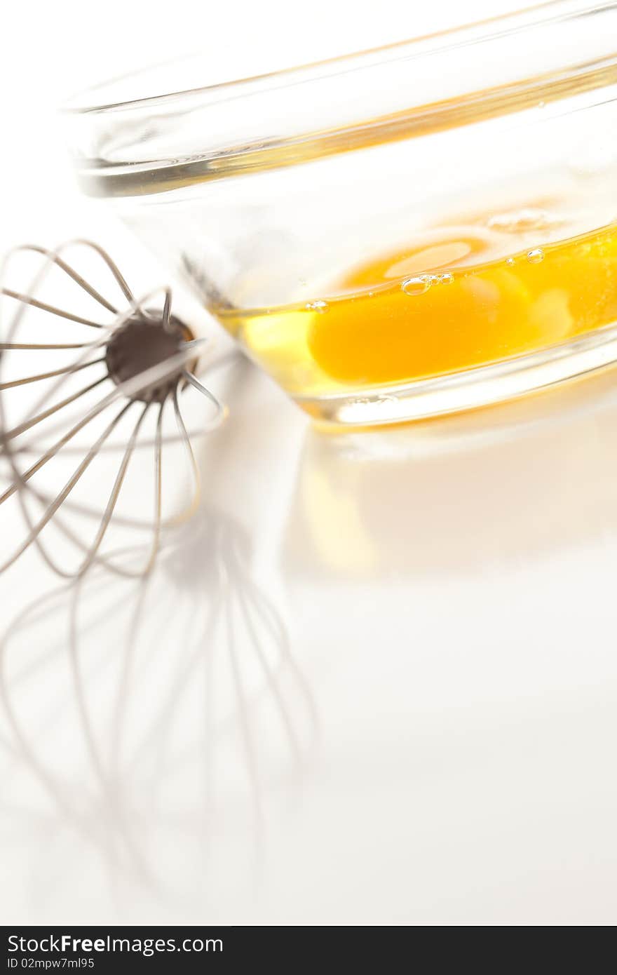 Hand Mixer with Eggs in a Glass Bowl on a Reflective White Background. Hand Mixer with Eggs in a Glass Bowl on a Reflective White Background.