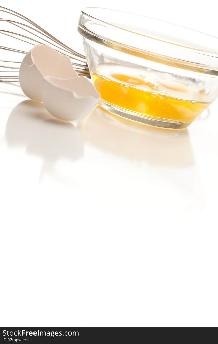 Hand Mixer with Eggs in a Glass Bowl and Shell on a Reflective White Background. Hand Mixer with Eggs in a Glass Bowl and Shell on a Reflective White Background.