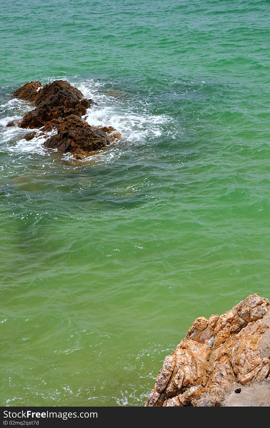 A small reef in blue and green water of sea, balance with big reef beside water. A small reef in blue and green water of sea, balance with big reef beside water.