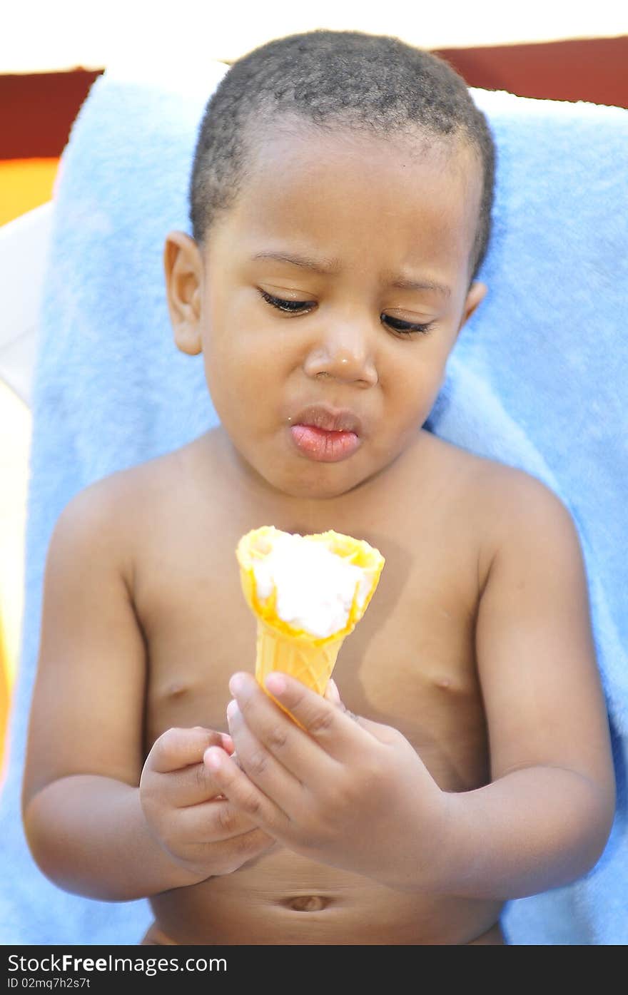 Child holding ice cream cone looking surprise while sitting in hot summer sun. Child holding ice cream cone looking surprise while sitting in hot summer sun