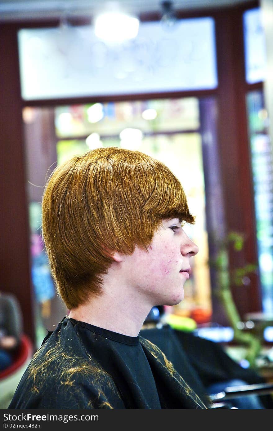 Smiling young boy with red hair at the hairdresser. Smiling young boy with red hair at the hairdresser