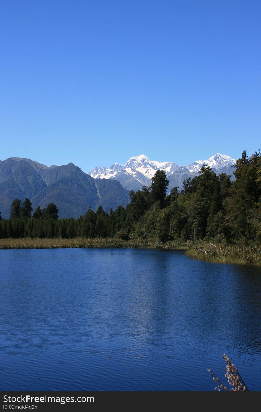 Mt Cook over the blue waters of Lake Matheson. Mt Cook over the blue waters of Lake Matheson.