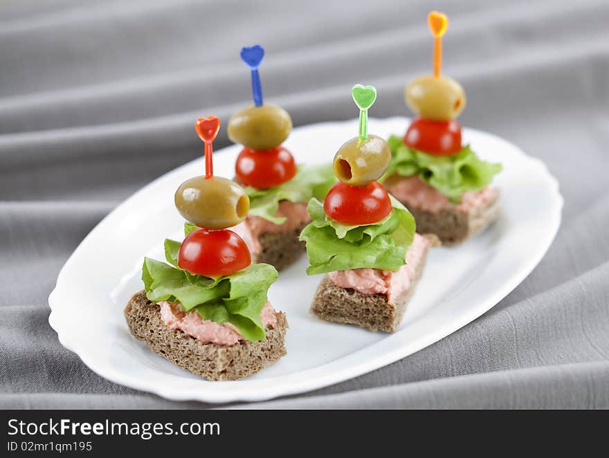 Close up of freshly made bites on white plate and grey cloth