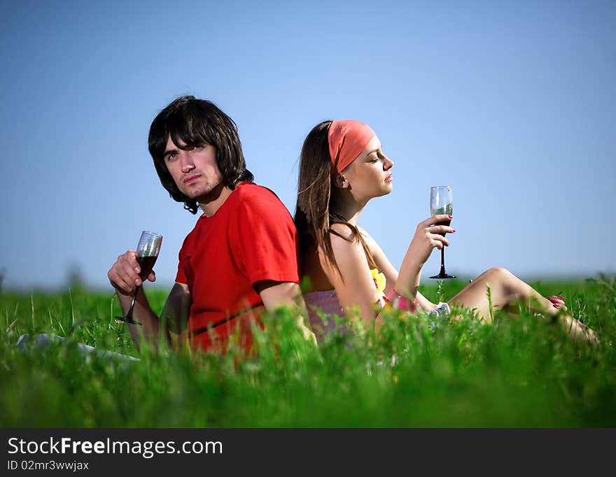 Boy and nice girl with wineglasses on grass