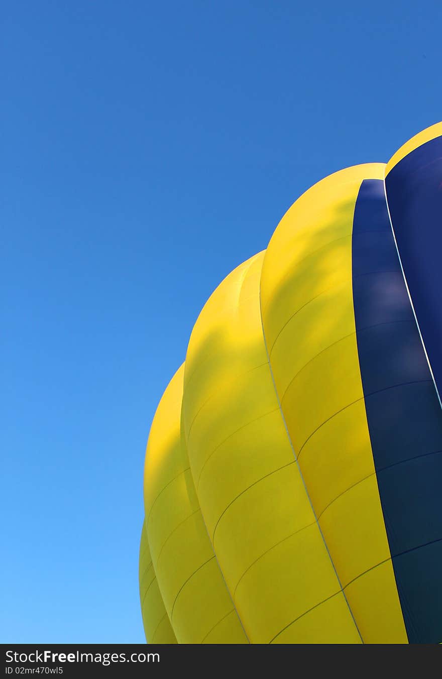 Yellow and blue hot air balloon on bright blue sky background. Yellow and blue hot air balloon on bright blue sky background