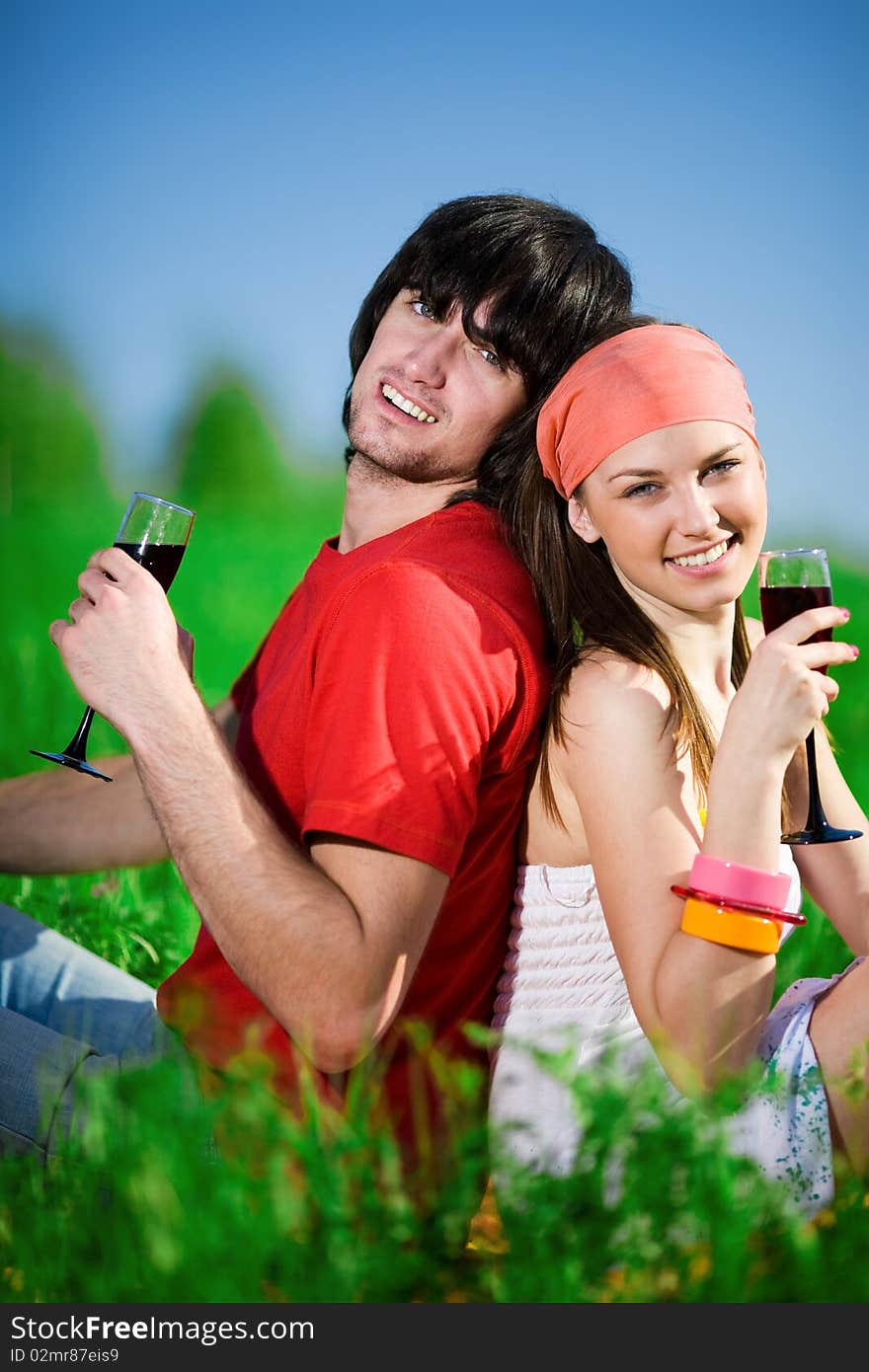 Girl and boy with wineglasses on grass