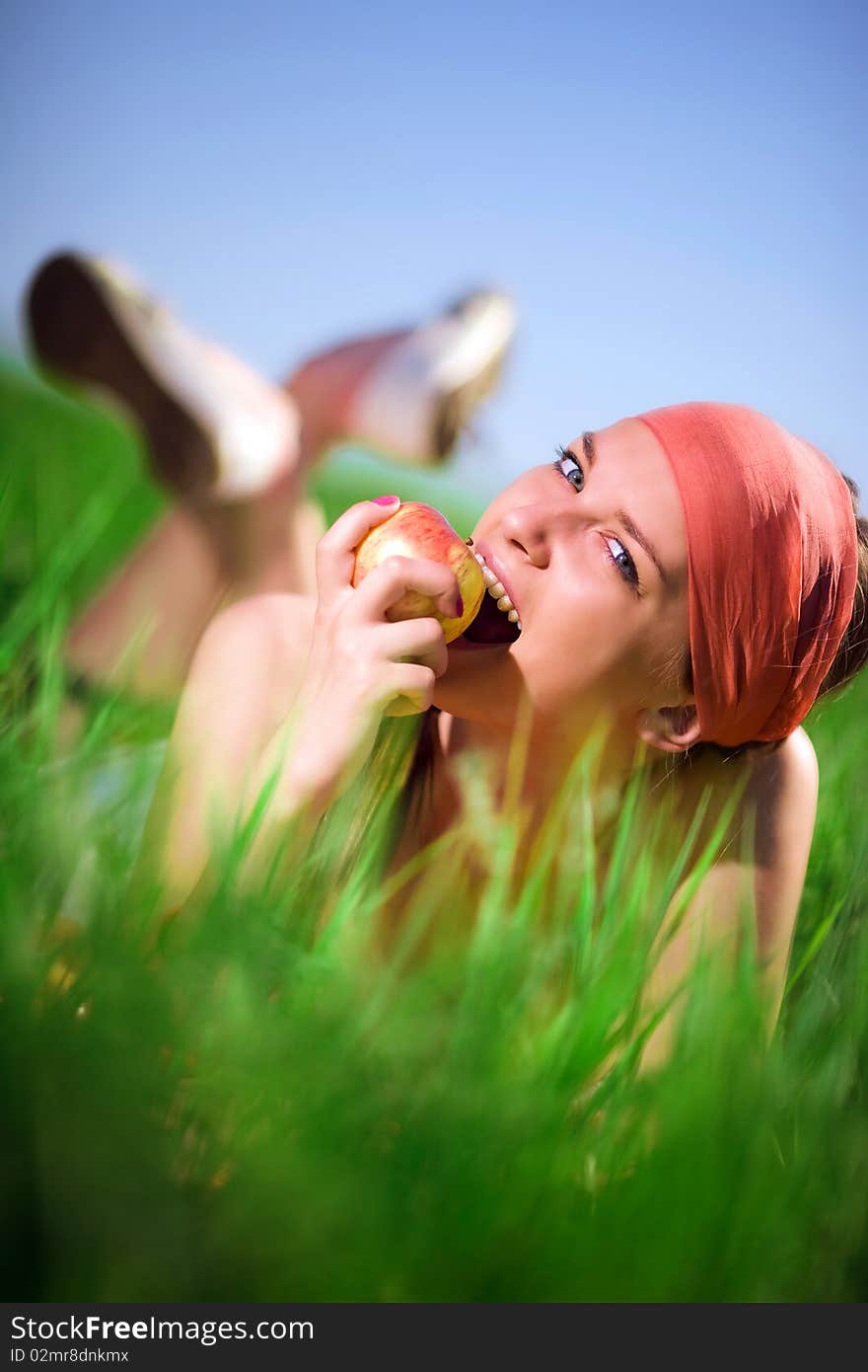 Girl in kerchief with apple on grass