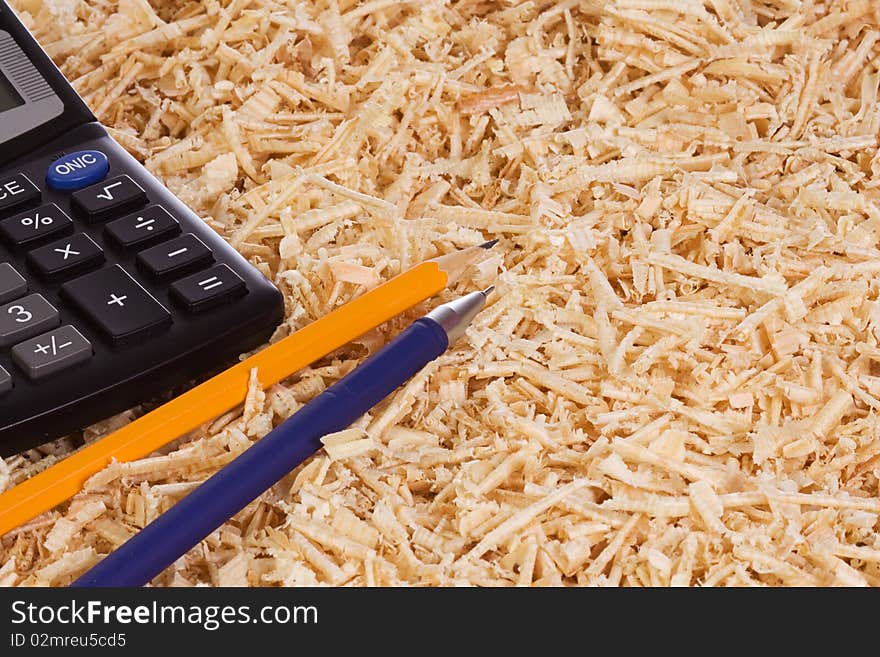 Calculator and pencil at wooden shaving