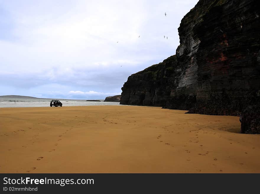 Four wheel drive car on ballybunion beach with cliffs in background. Four wheel drive car on ballybunion beach with cliffs in background