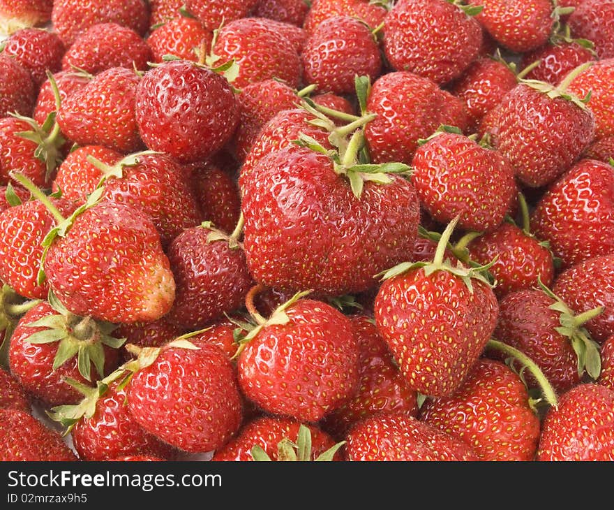 Red ripe strawberries poured on the table in several layers under natural light. Red ripe strawberries poured on the table in several layers under natural light