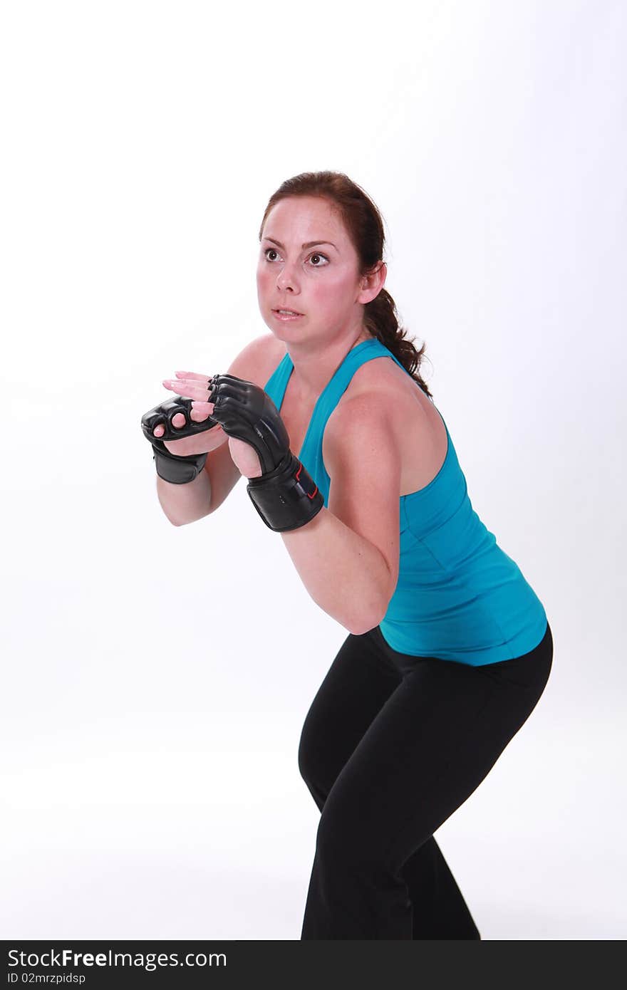 A woman stands with mixed martial arts gloves in defense stance. A woman stands with mixed martial arts gloves in defense stance.