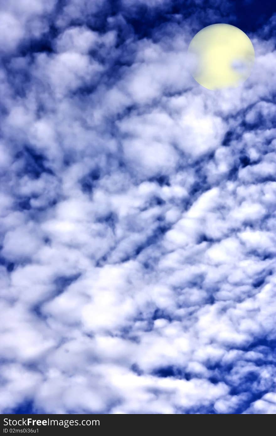 A deep blue sky with white clouds and a moon. A deep blue sky with white clouds and a moon