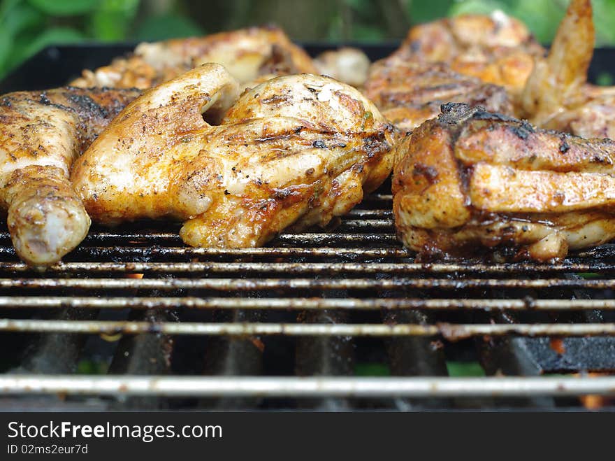 Pieces of chicken on metal grill. Pieces of chicken on metal grill