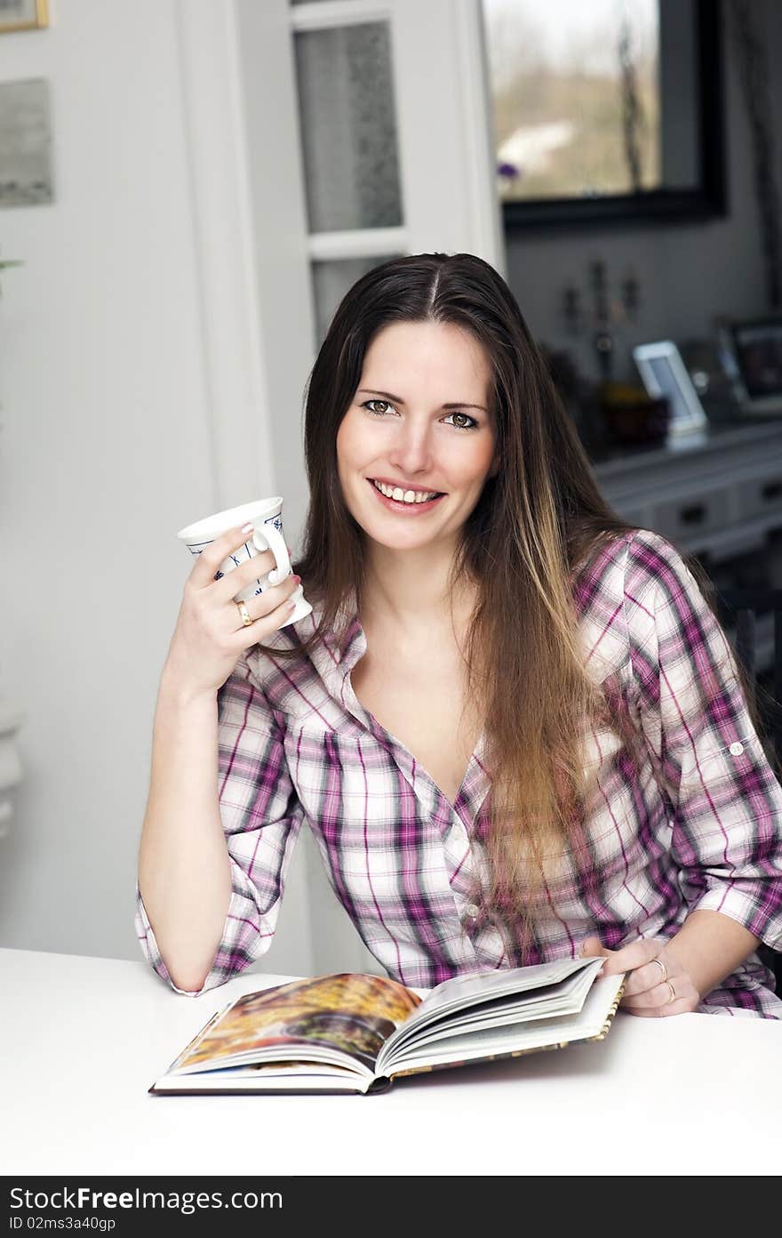 Young woman reading a book and drinking a coffee. Young woman reading a book and drinking a coffee