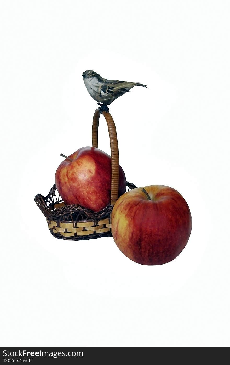 One red apple lying in a basket, the second is located nearby. Basket on the handle sits artificial bird. photo. One red apple lying in a basket, the second is located nearby. Basket on the handle sits artificial bird. photo