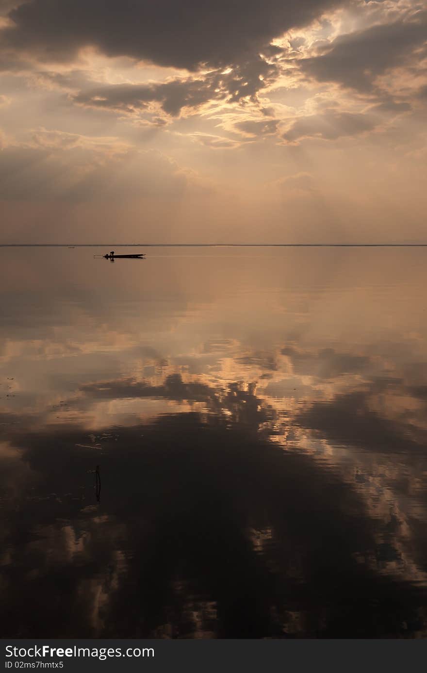 Silhouette of a small boat on mirror-reflected dam