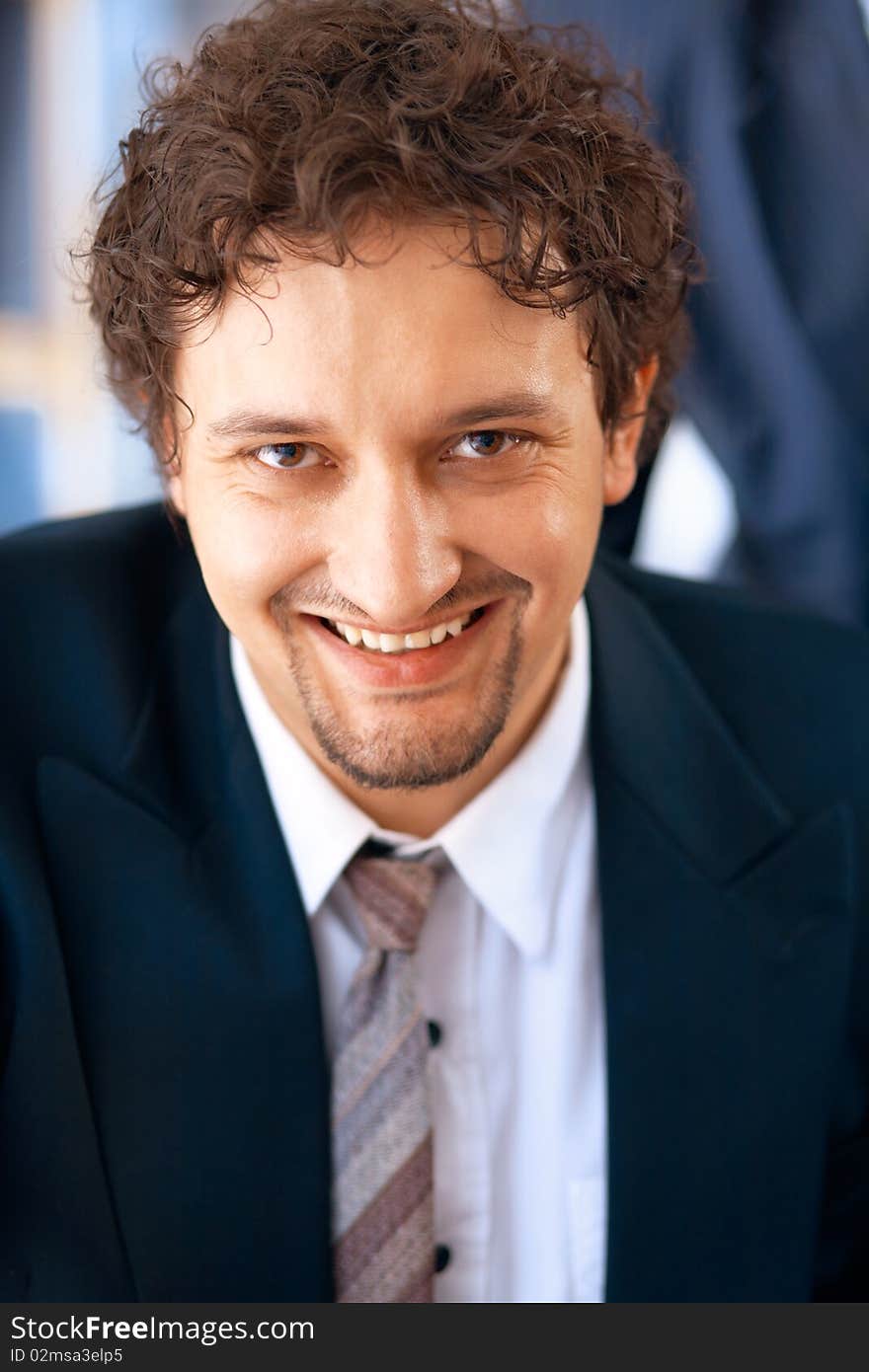 Young smiling businessman working on laptop in the office