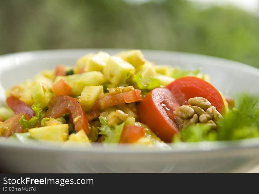 Delicious salad with fresh raw vegetables. Salad is made of: zucchini, walnuts, tomato, cucumber, lettuce leaves, turmeric, salt, oil from walnuts.