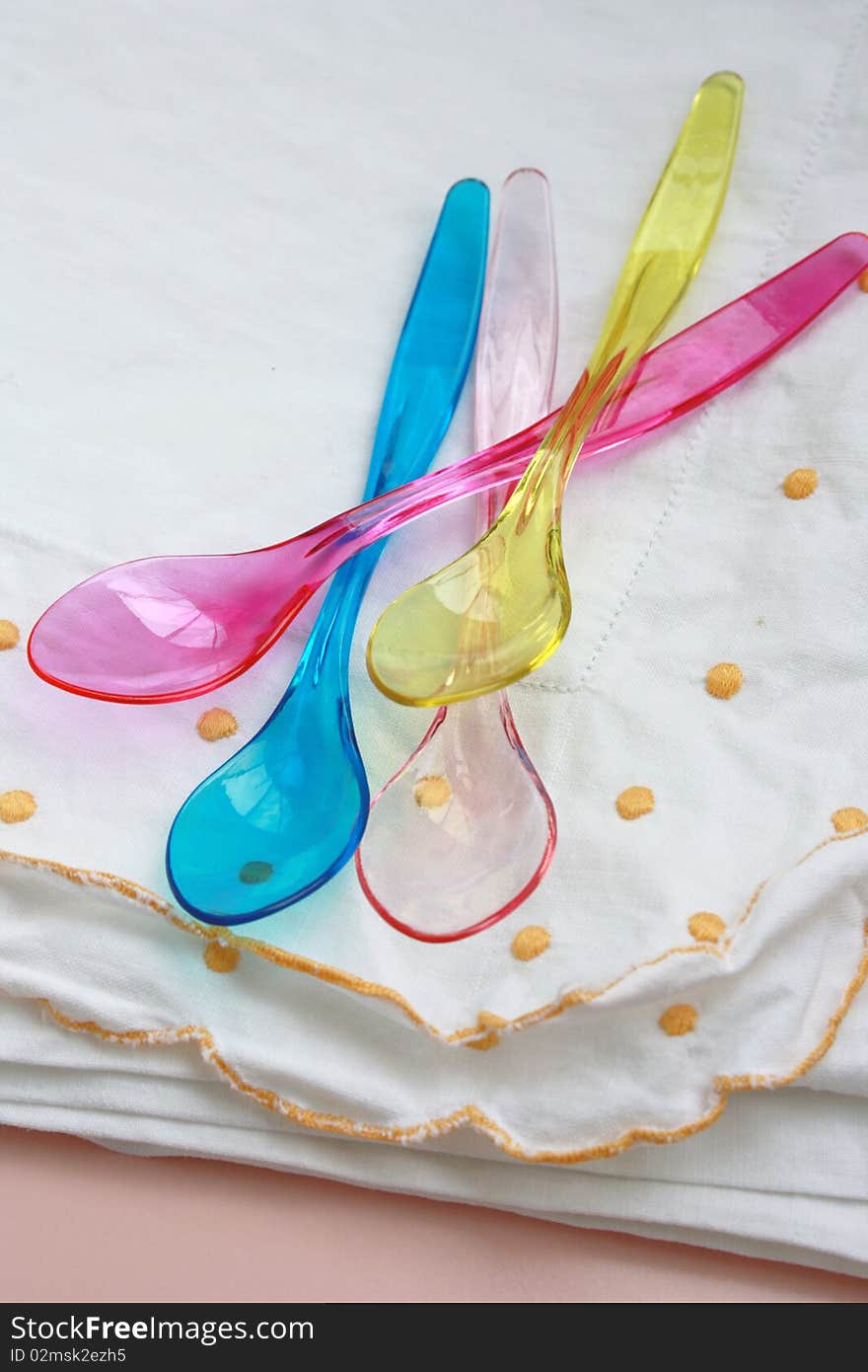 A colorful plastic spoons on a white kitchen towel