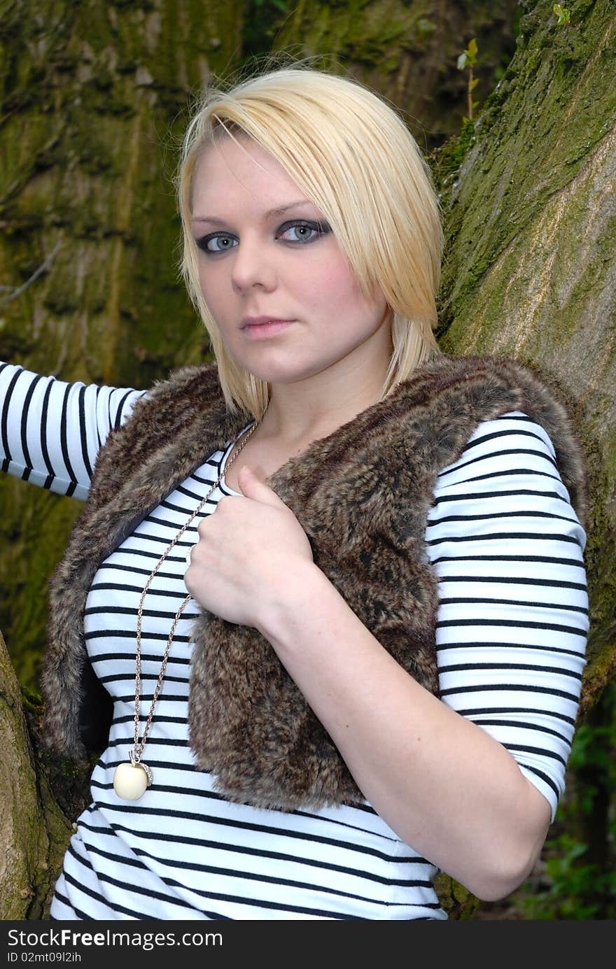 Photograph of pretty blond girl posing against tree. Photograph of pretty blond girl posing against tree