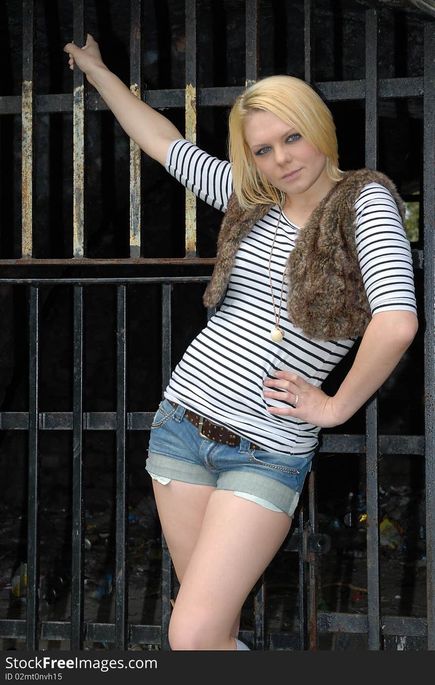 Blond Girl Posing Against Metal Gate