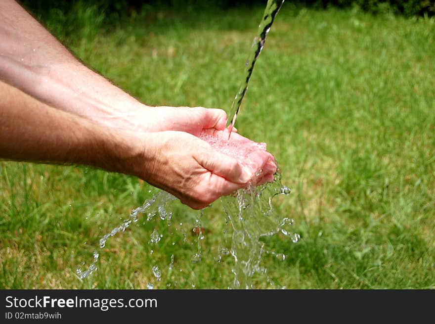 Man's cupped hands full to overflowing with fresh water. Man's cupped hands full to overflowing with fresh water