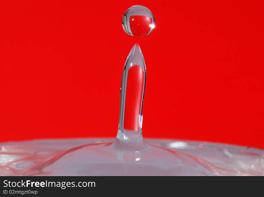 Water drop splashed with red background.