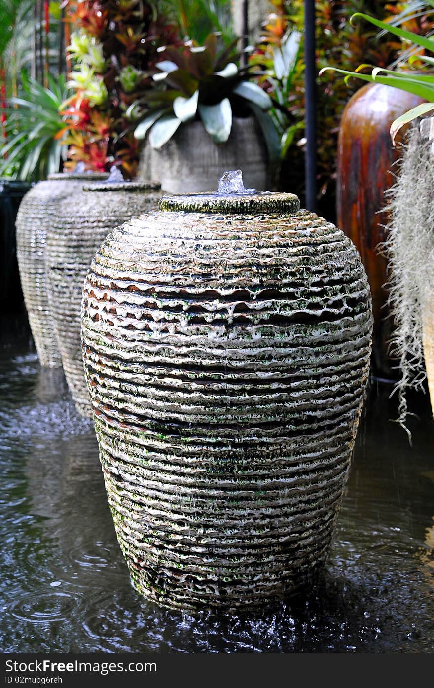 Terracotta Pottery in a water ditch with colorful plants in the background