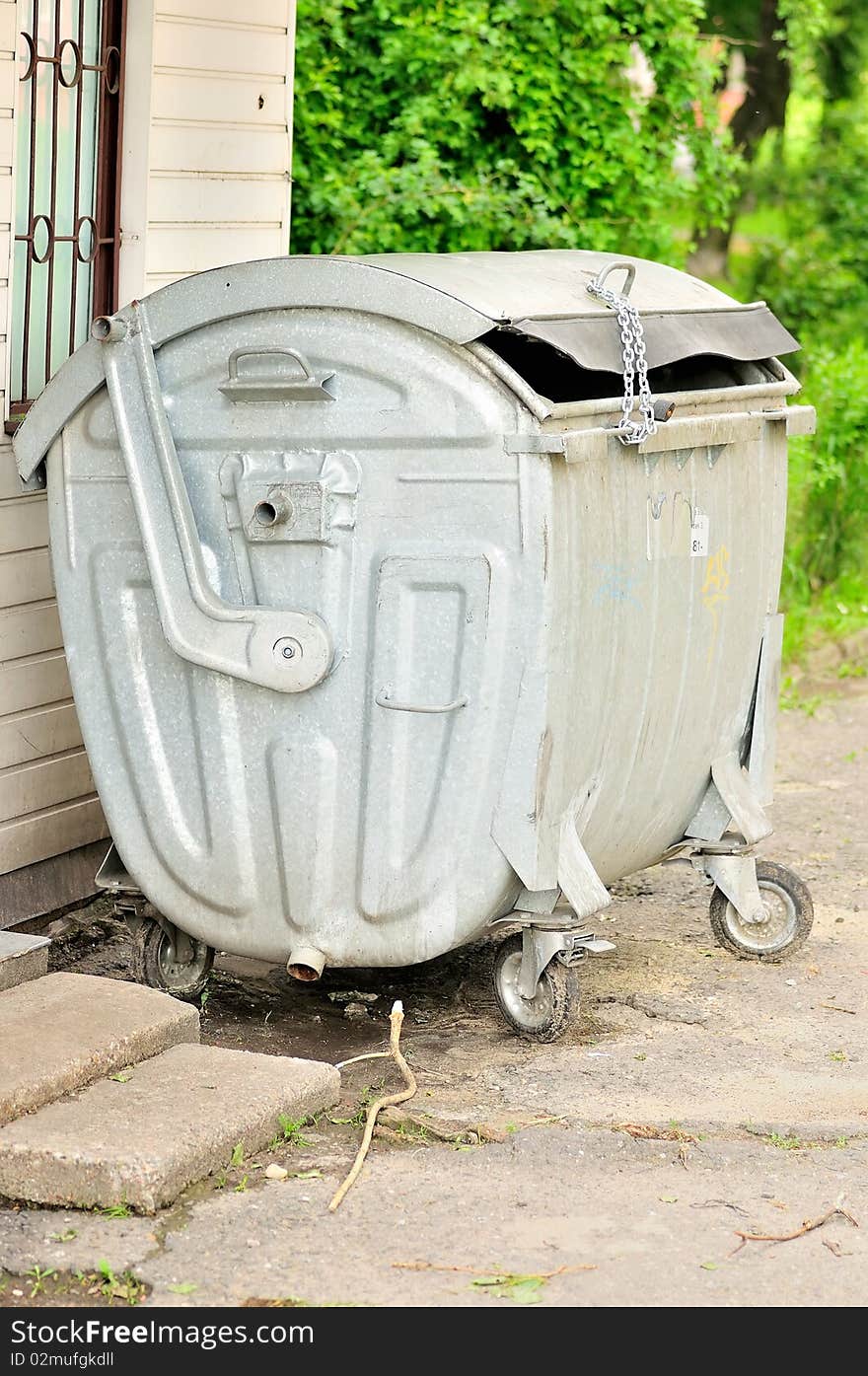 The photo shows a rubbish, rubbish container on a closed chain with a padlock. The photo shows a rubbish, rubbish container on a closed chain with a padlock.