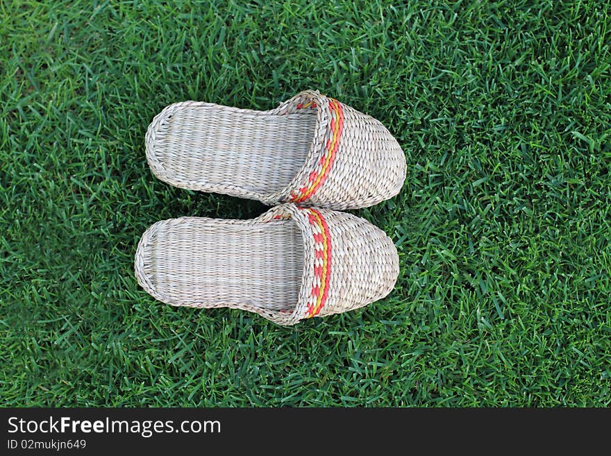 Footwear hand made from straw on the green grass. Footwear hand made from straw on the green grass