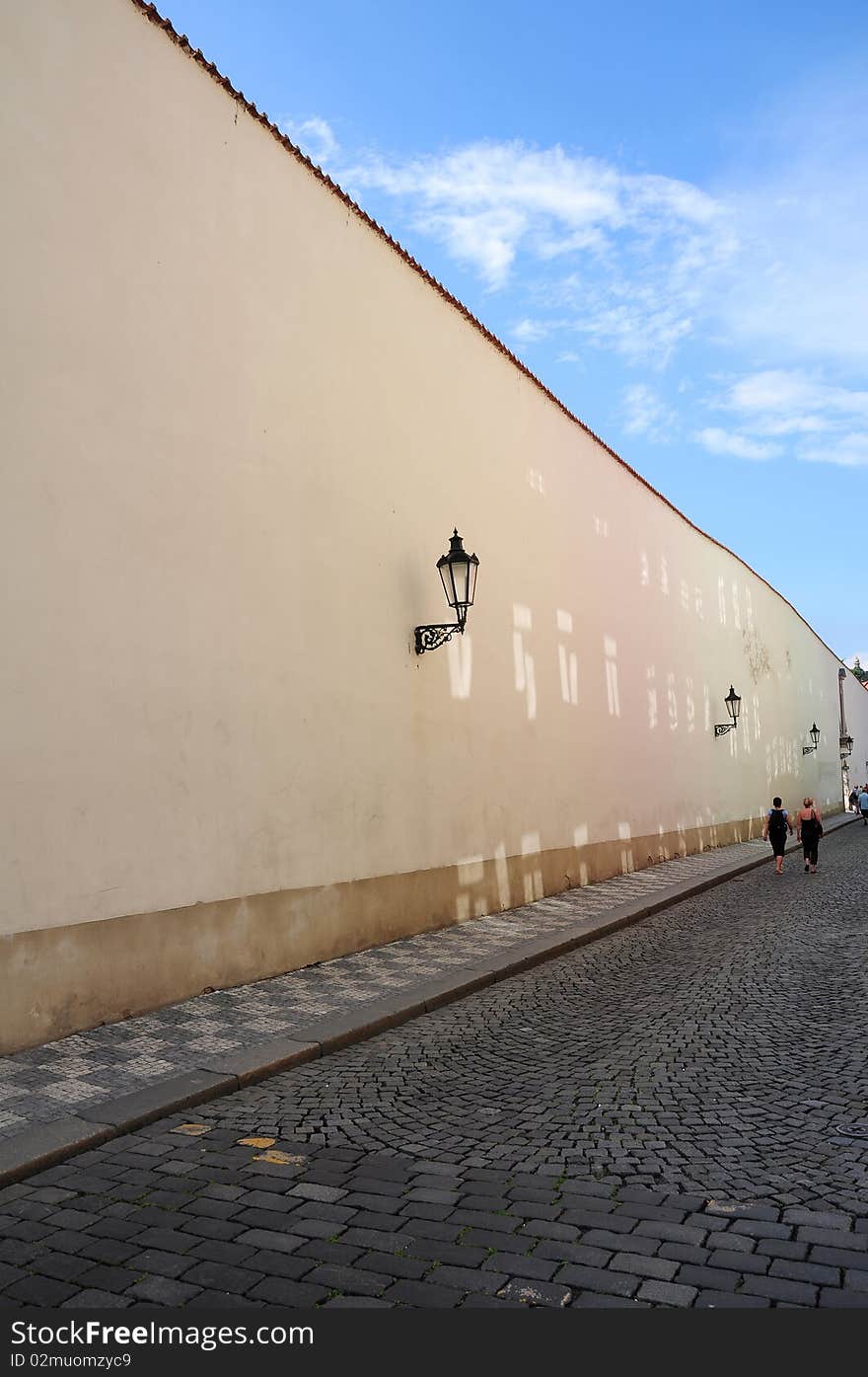 Two weman walking in an old street near a wall, Prague