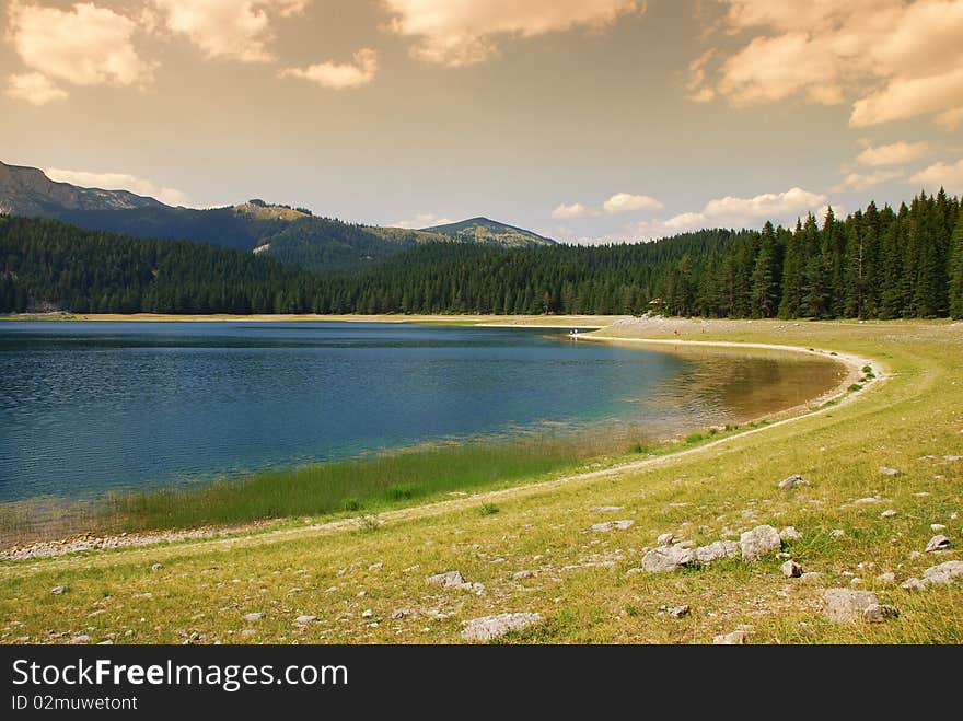 Mountain lake pine forest and clouds