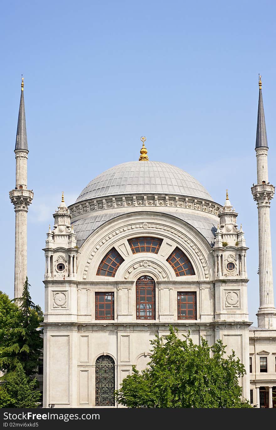 A small ornate mosque against a blue sky background. A small ornate mosque against a blue sky background