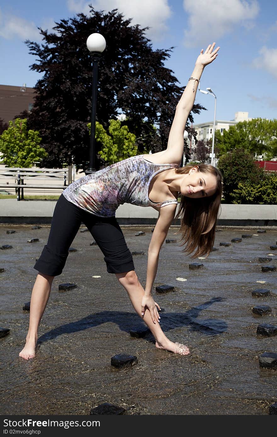 A woman doing her stretching a exercising in a park in some water to cool her off. A woman doing her stretching a exercising in a park in some water to cool her off.