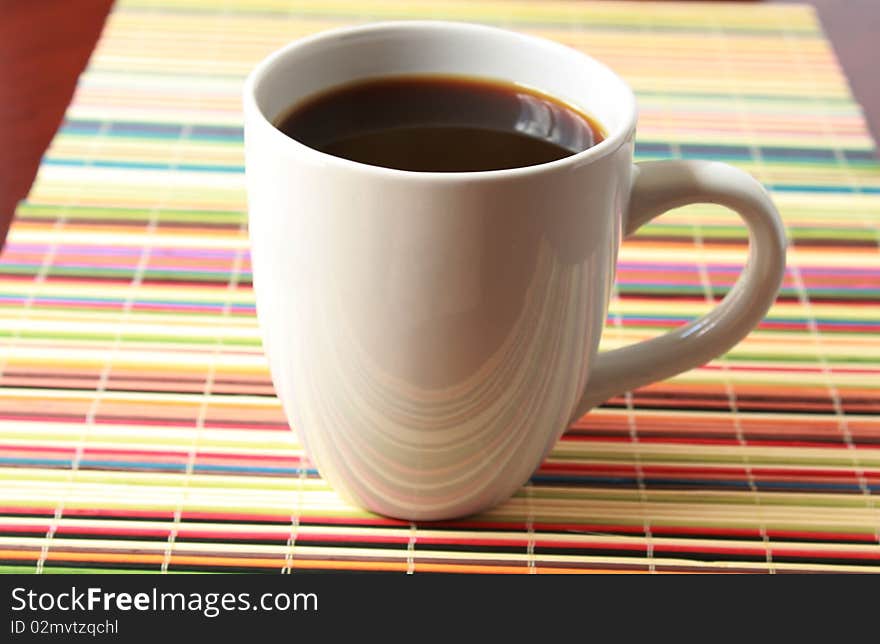 White cup with coffee on placemat