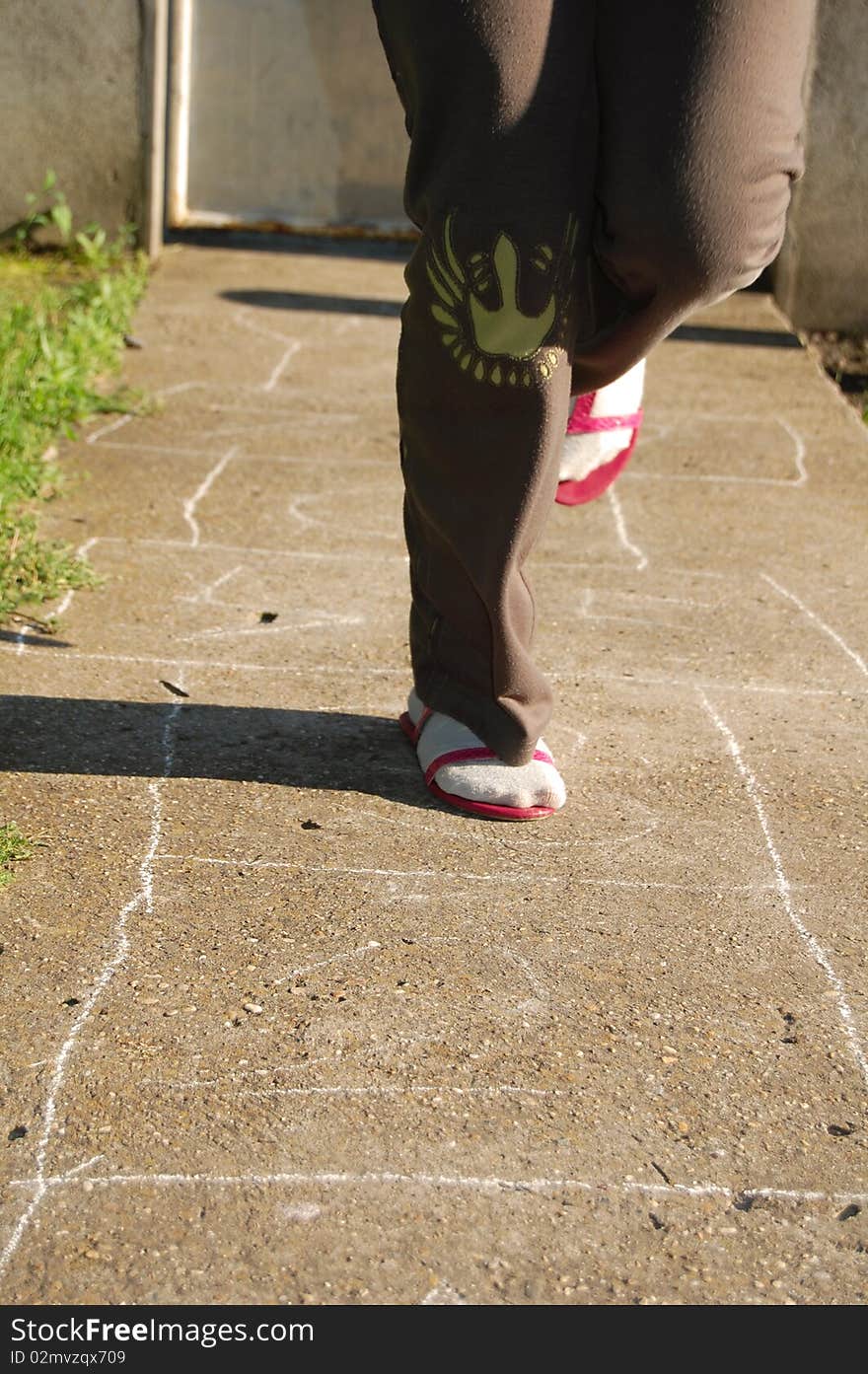 Child hopping on a hopscotch game painted on pavement. Child hopping on a hopscotch game painted on pavement