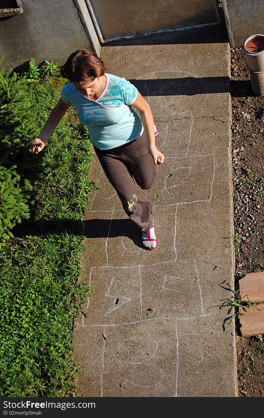 Girl hopping on a hopscotch game painted on pavement. Girl hopping on a hopscotch game painted on pavement