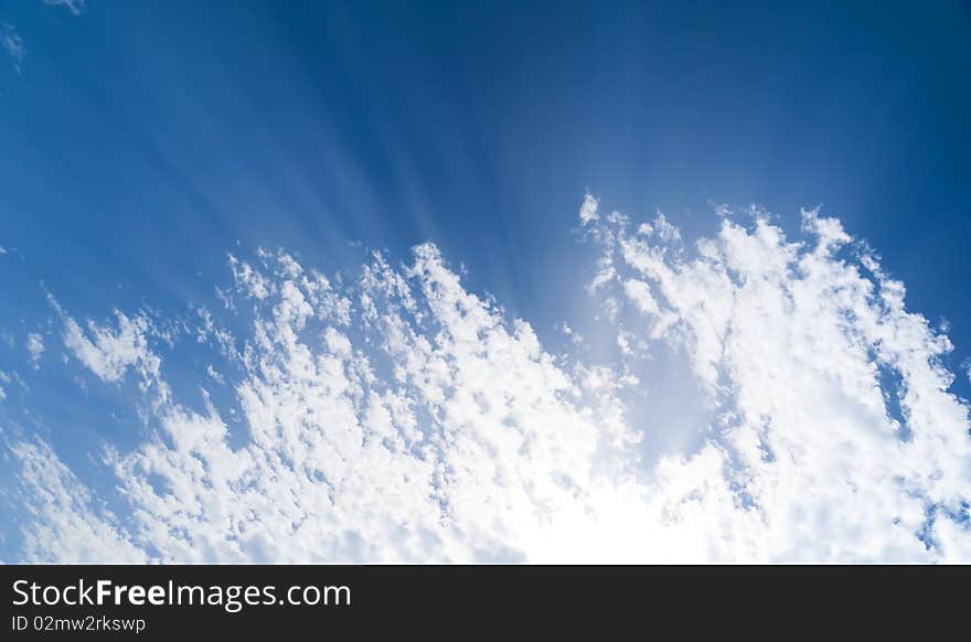 The blue sky and sun beams shining through clouds