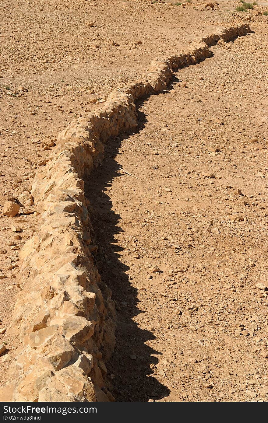 Curved wall of ancient fortress ruin in yellow desert