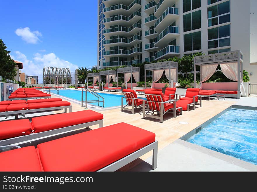 A contemporary luxury pool with modern red and white cabanas.