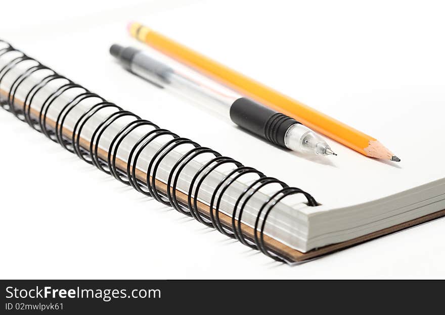 A spiral sketchbook or notepad with one mechanical and one standard pencil on top, closeup. A spiral sketchbook or notepad with one mechanical and one standard pencil on top, closeup