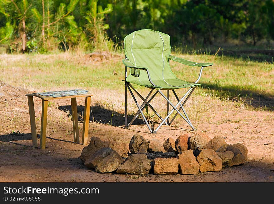 Folding chair and table next to a fire ring. Folding chair and table next to a fire ring.