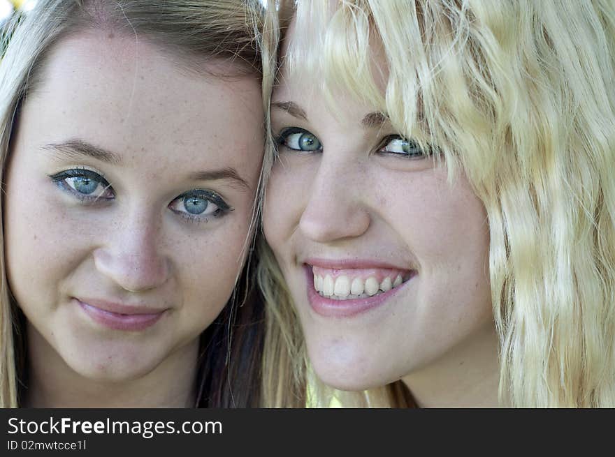 Closeup photograph of two pretty blond girl friends smiling at the camera. Closeup photograph of two pretty blond girl friends smiling at the camera.