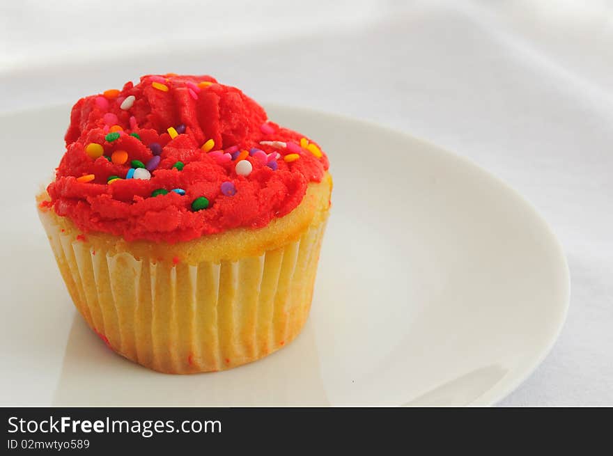 Single red cupcake on a small white dish with white background. Single red cupcake on a small white dish with white background